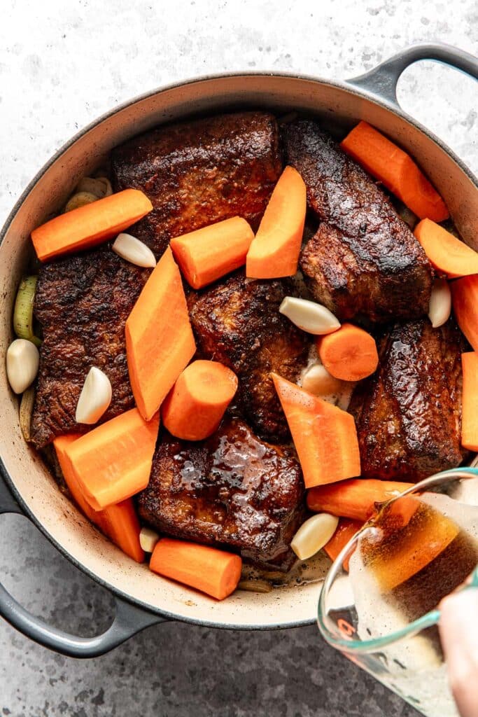 Beer being poured over the seared brisket and veggies