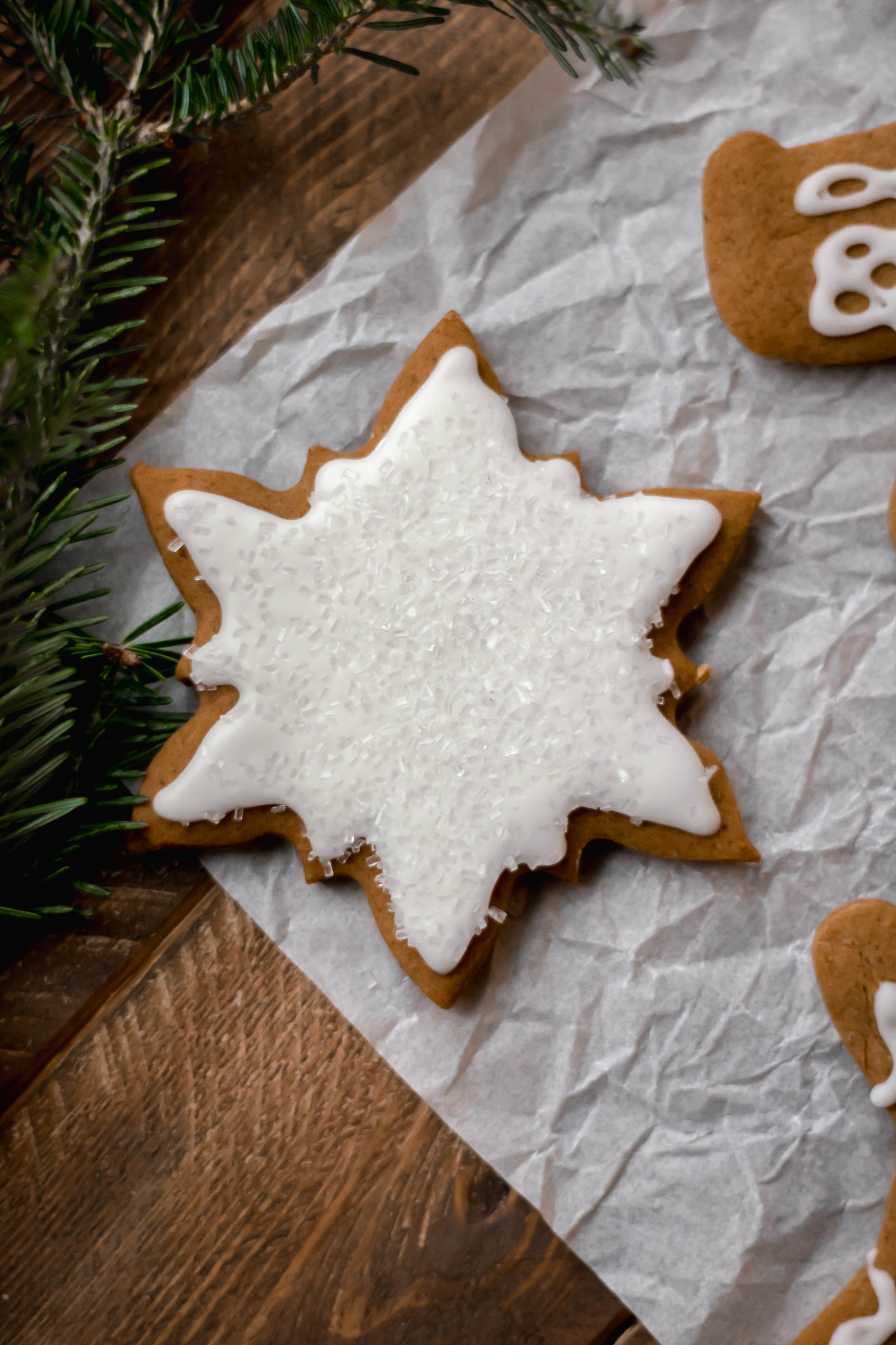 A snowflake shaped gingerbread cookie topped with cream cheese icing 