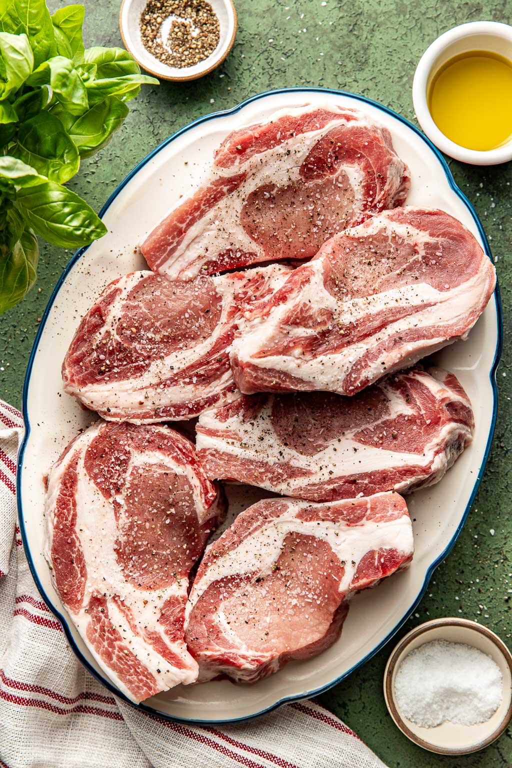 Pork chops on a plate after being seasoned