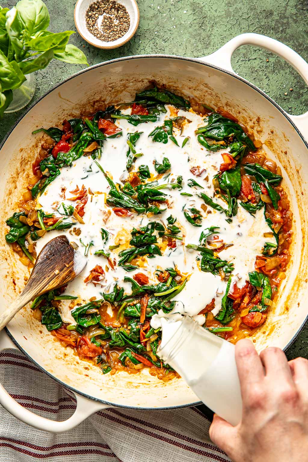 Cream and spinach being added to the tomatoes