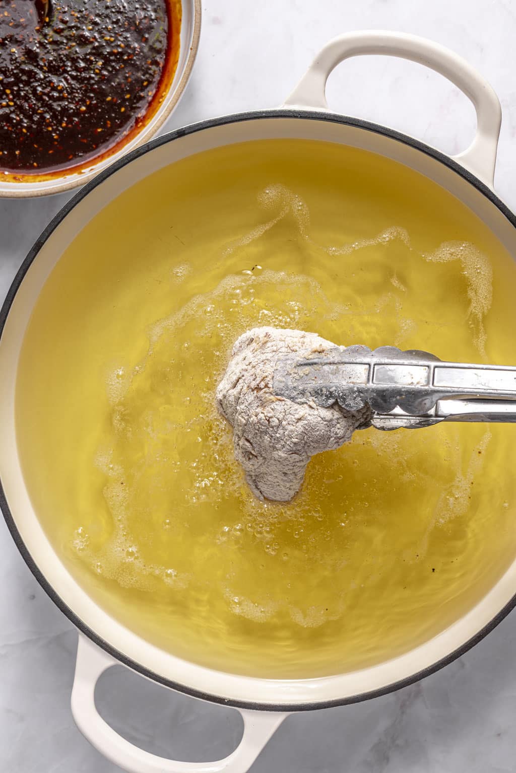 chicken being lowered into a pot of hot oil