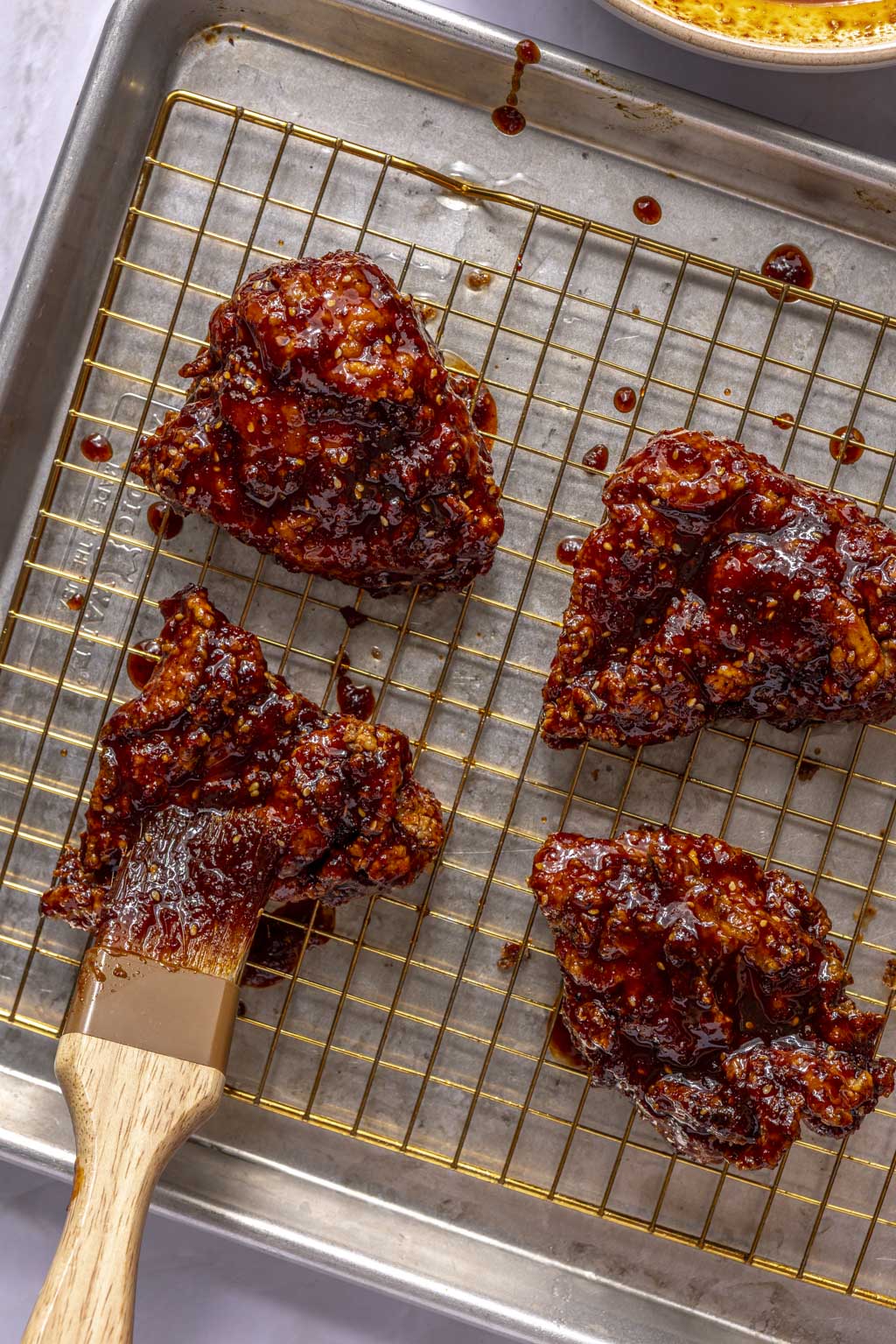 glaze being brushed onto pieces of fried chicken