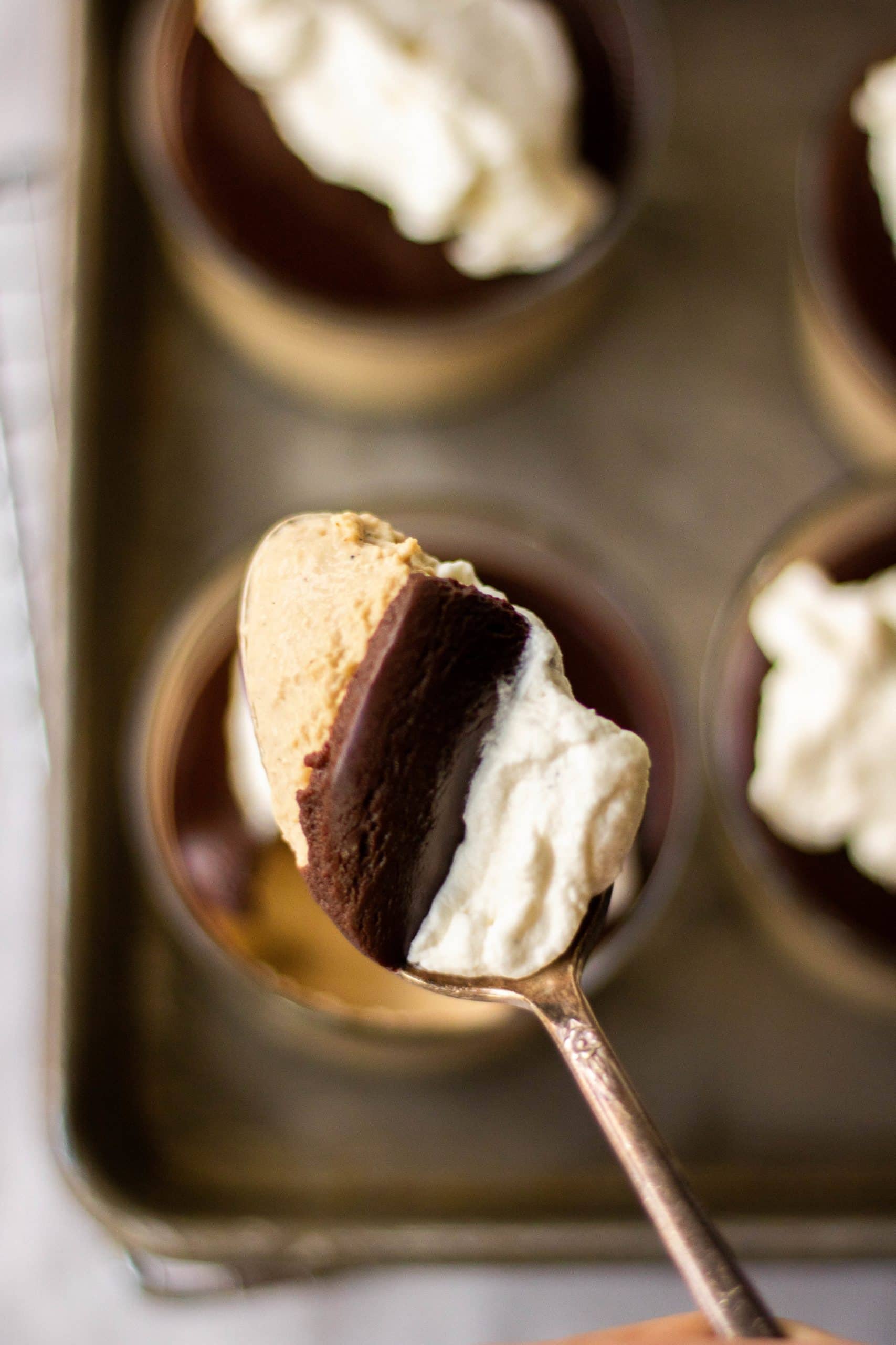 A spoonful of coffee panna cotta topped with chocolate ganache and mascarpone whipped cream. 