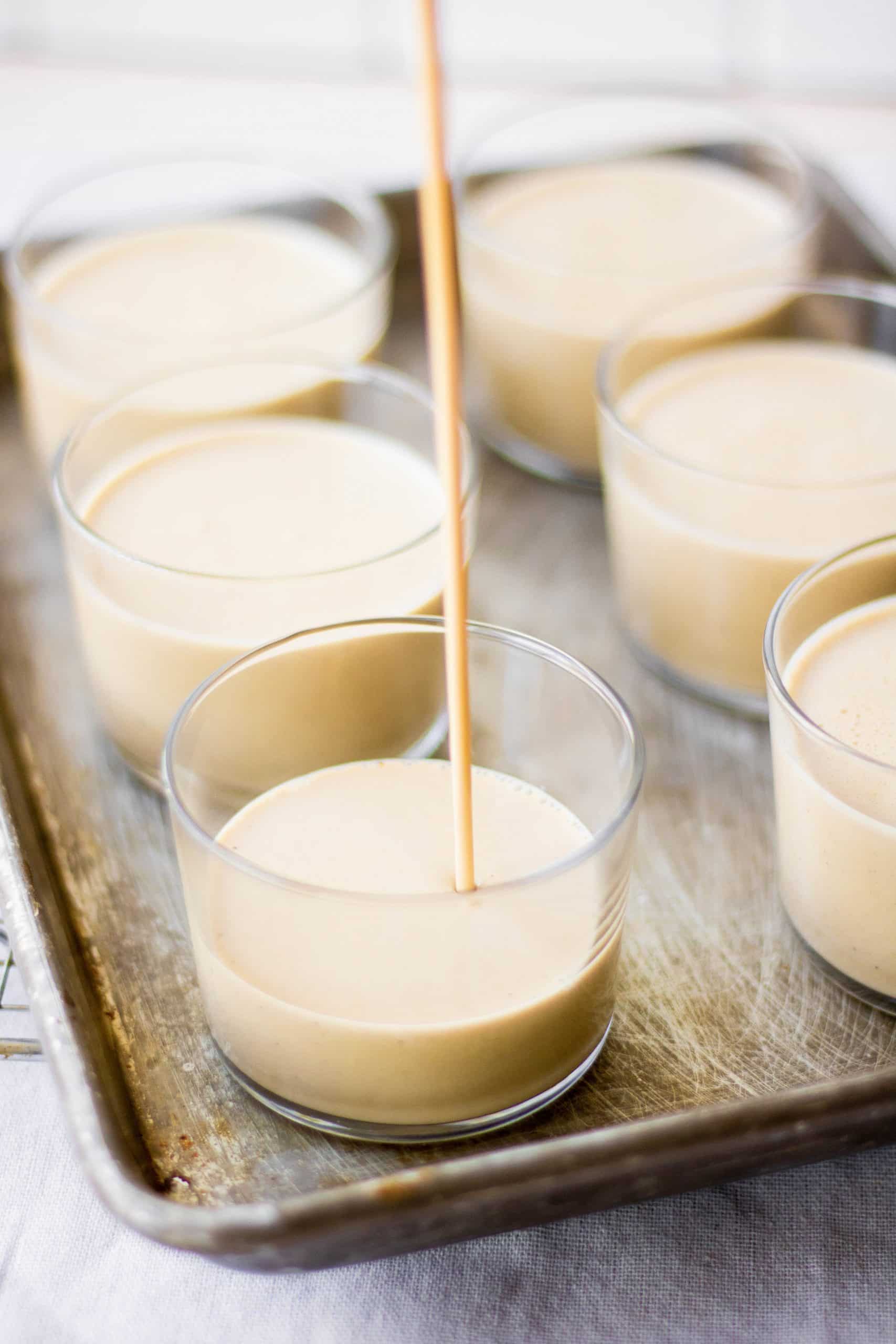 Panna cotta mixture being poured into glass jars. 