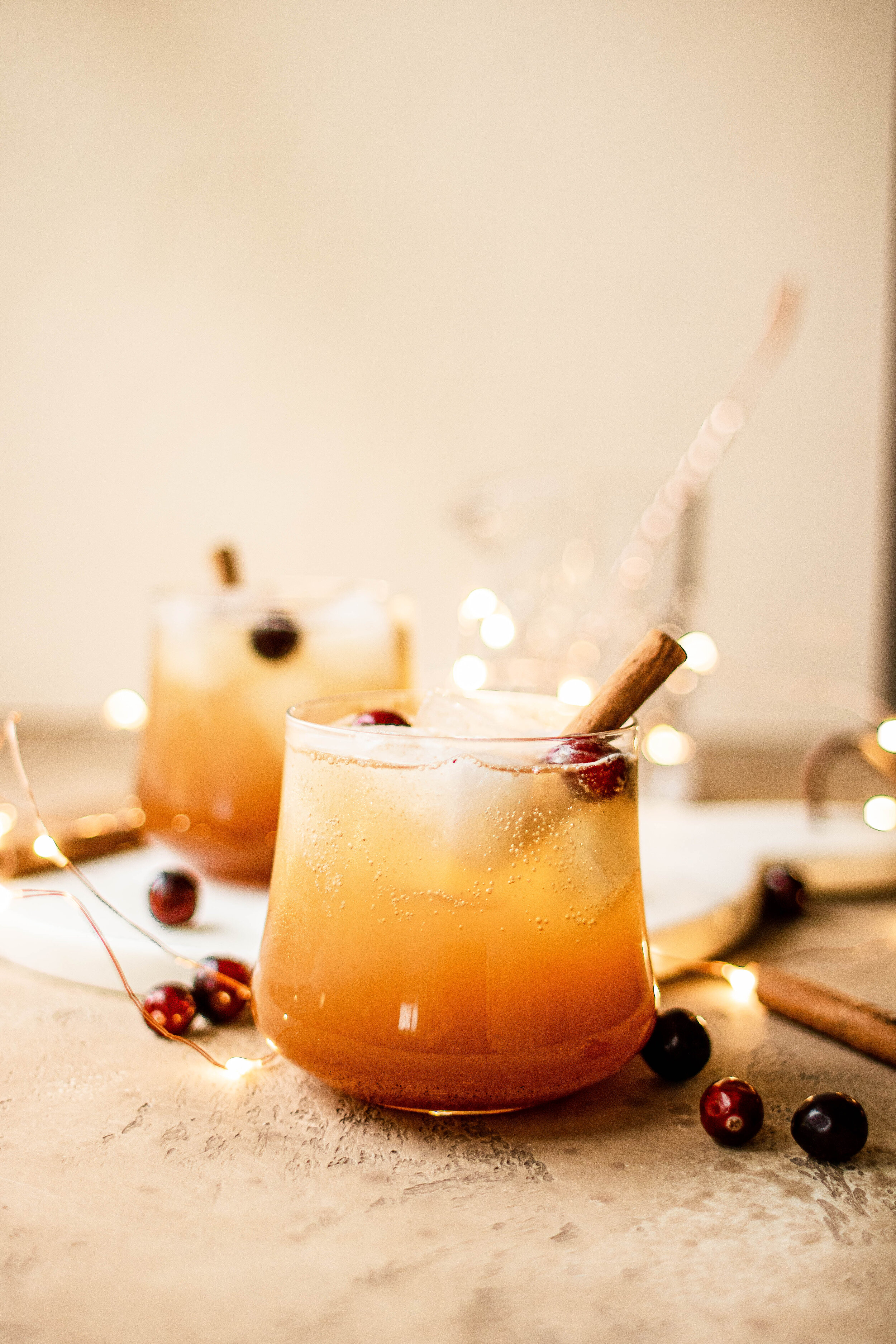 a sparkling bourbon apple cider cocktail in a glass, garnished with a cinnamon stick 