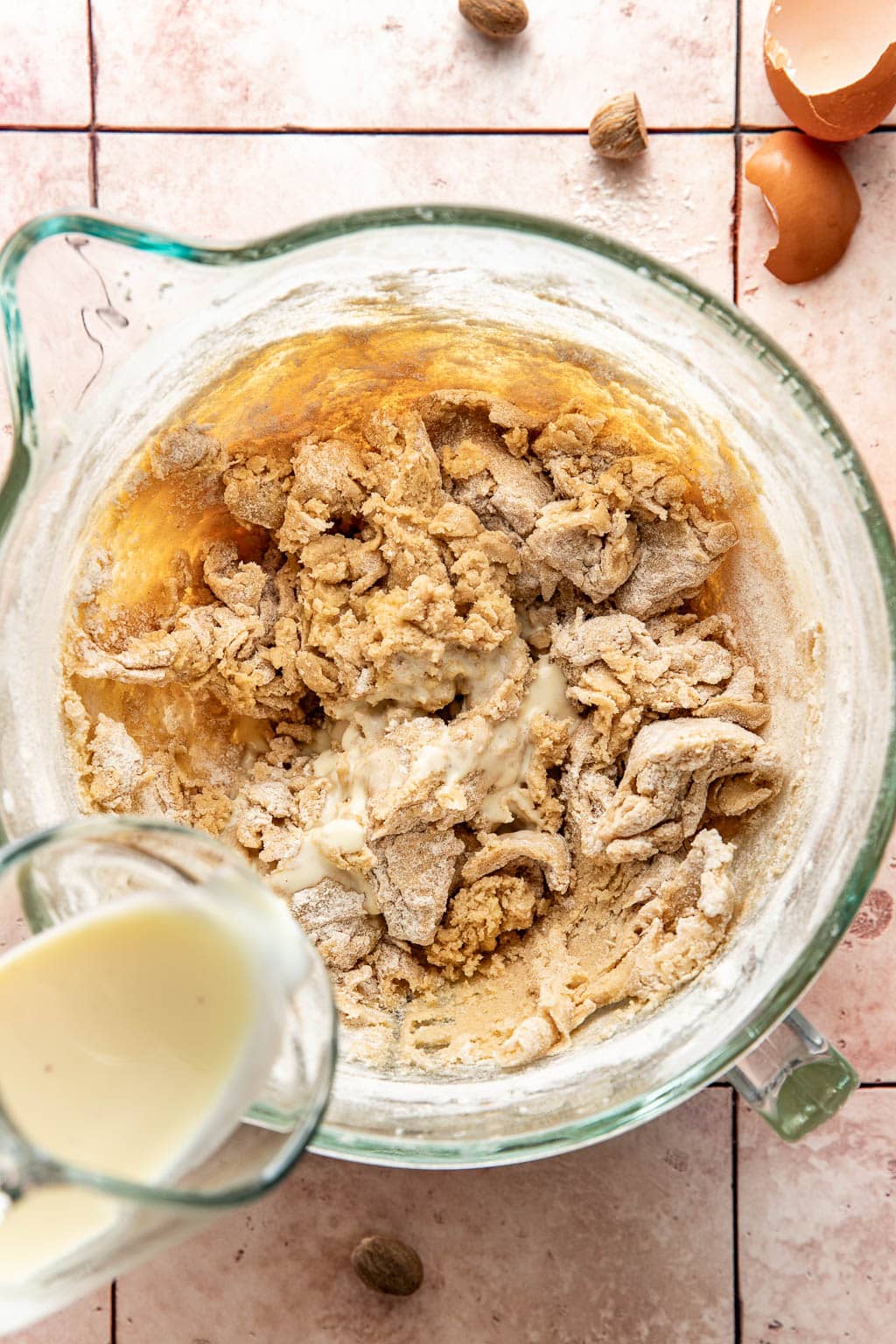 pouring eggnog into the cookie dough while its mixing