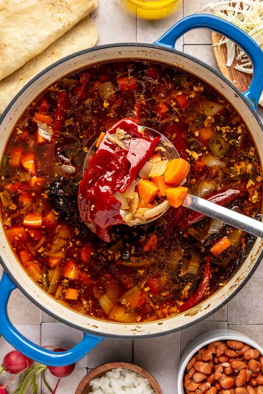 Fishing out the vegetables from a pot of pozole rojo 
