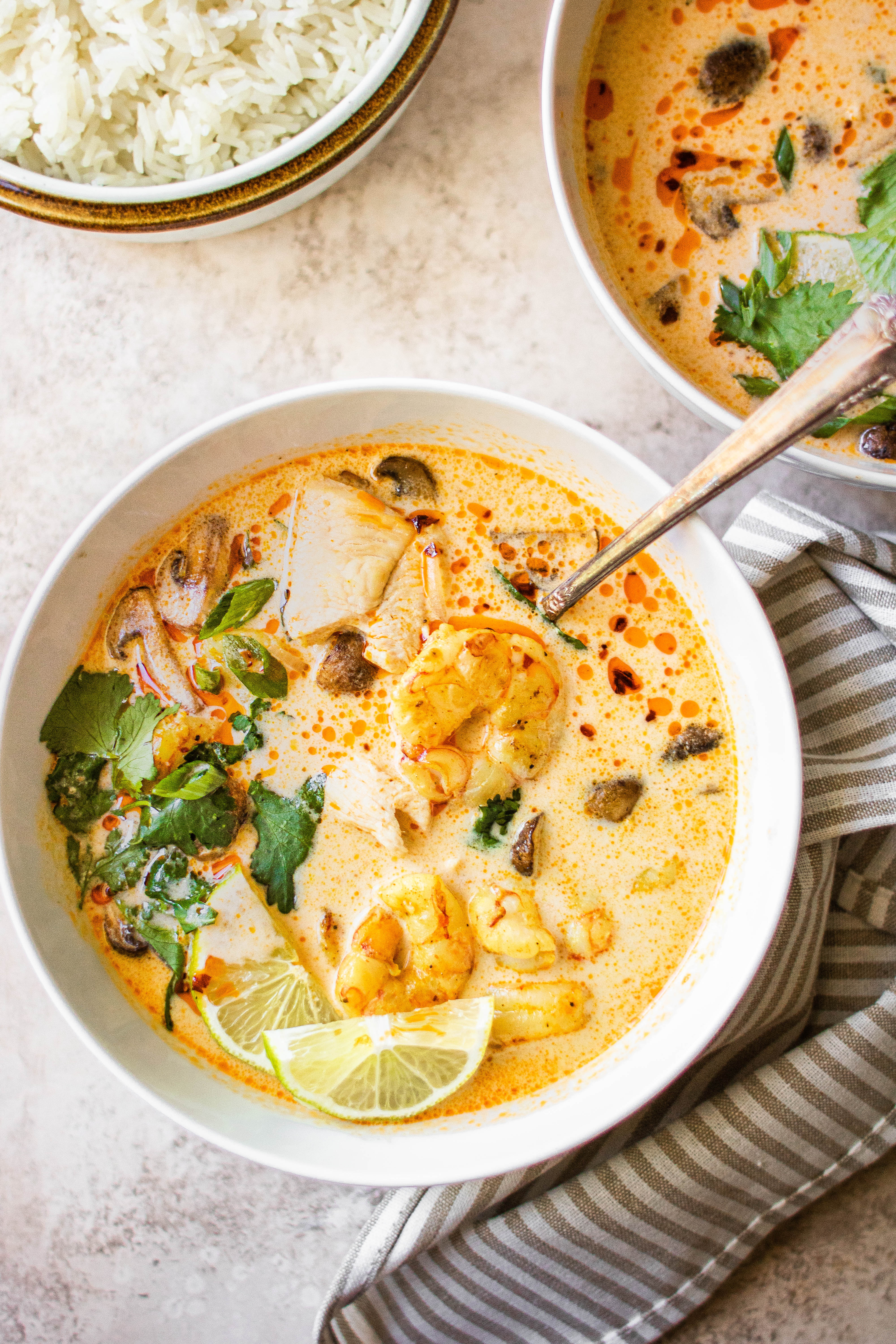 A bowl of Tom Kha Gai soup garnished with cilantro and lime 