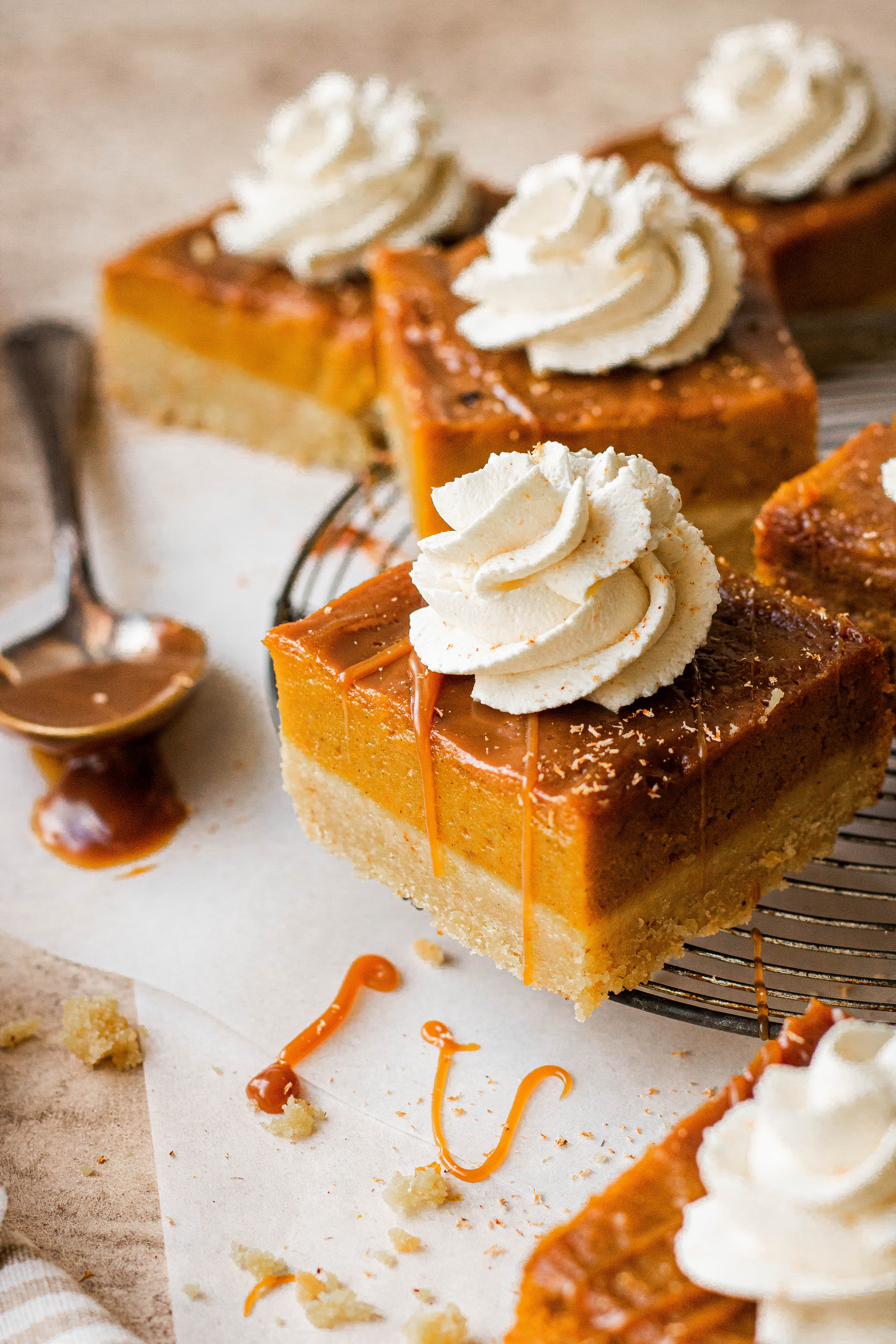 A pumpkin pie bar topped with maple whipped cream and salted caramel sauce