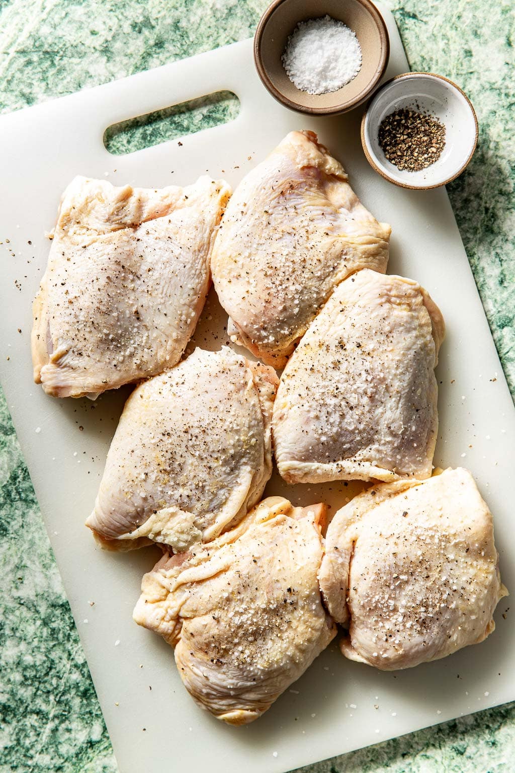 Seasoned chicken thighs on a cutting board
