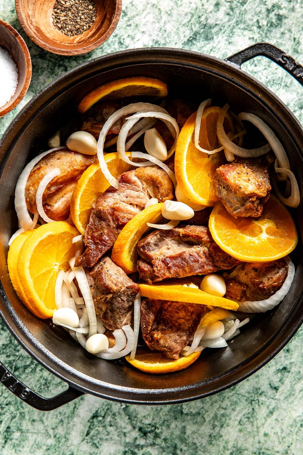 seared pork, onion, and oranges in a dutch oven