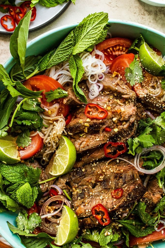 Thai beef salad with rice noodles and fresh herbs in a big bowl 