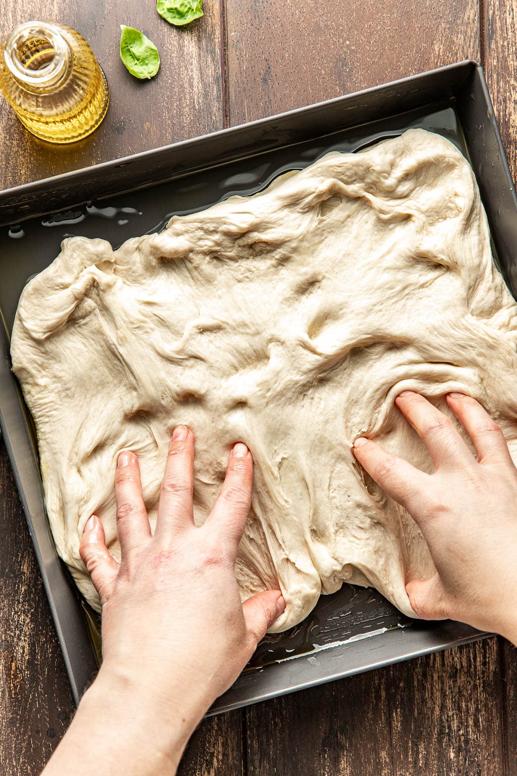 Pizza dough being stretched to fit the pizza pan