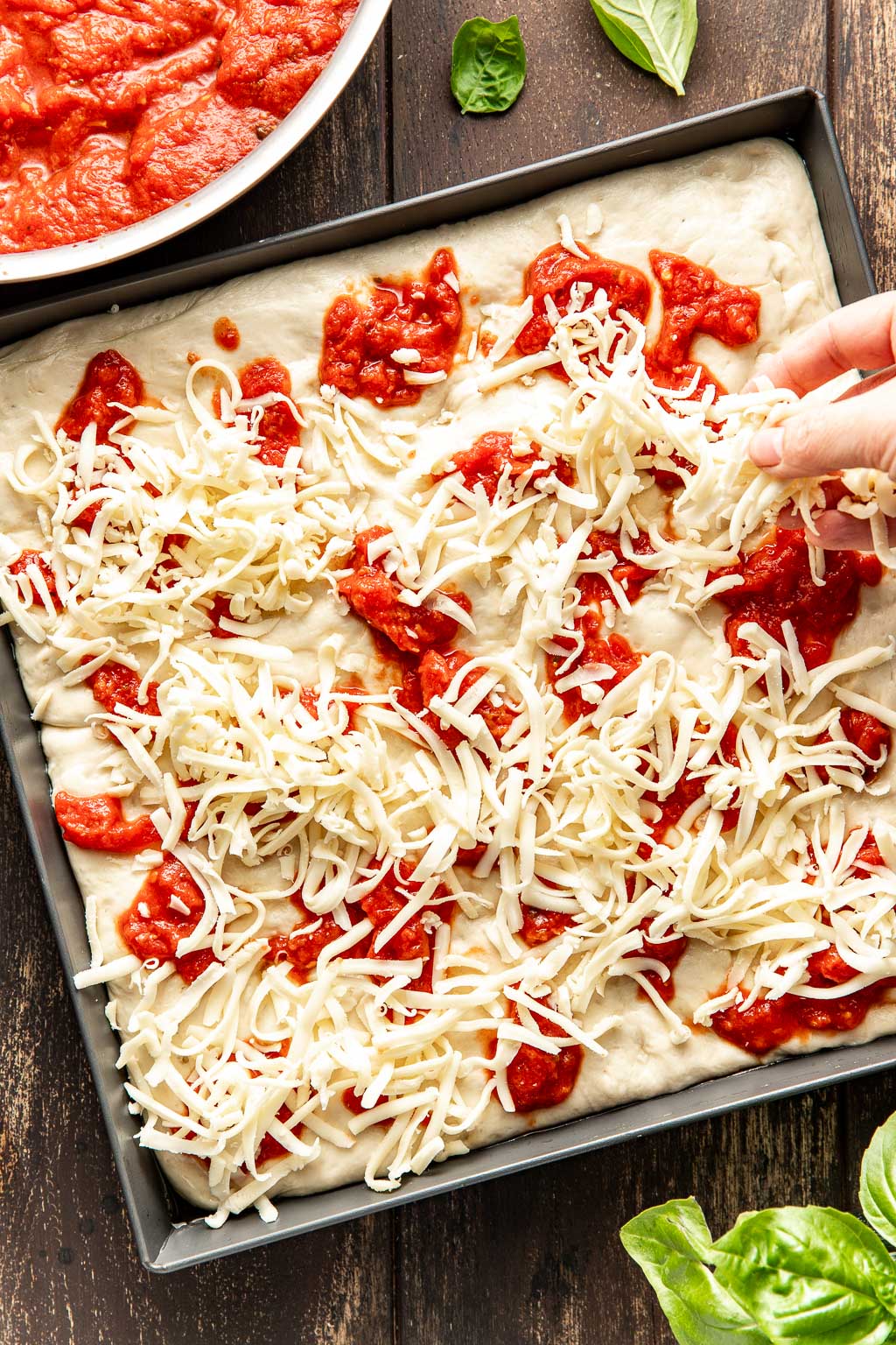 Sprinkling cheese and sauce on pizza dough