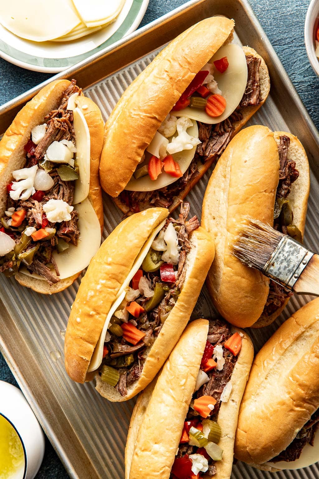 assembled italian beef sandwiches being brushed with garlic butter