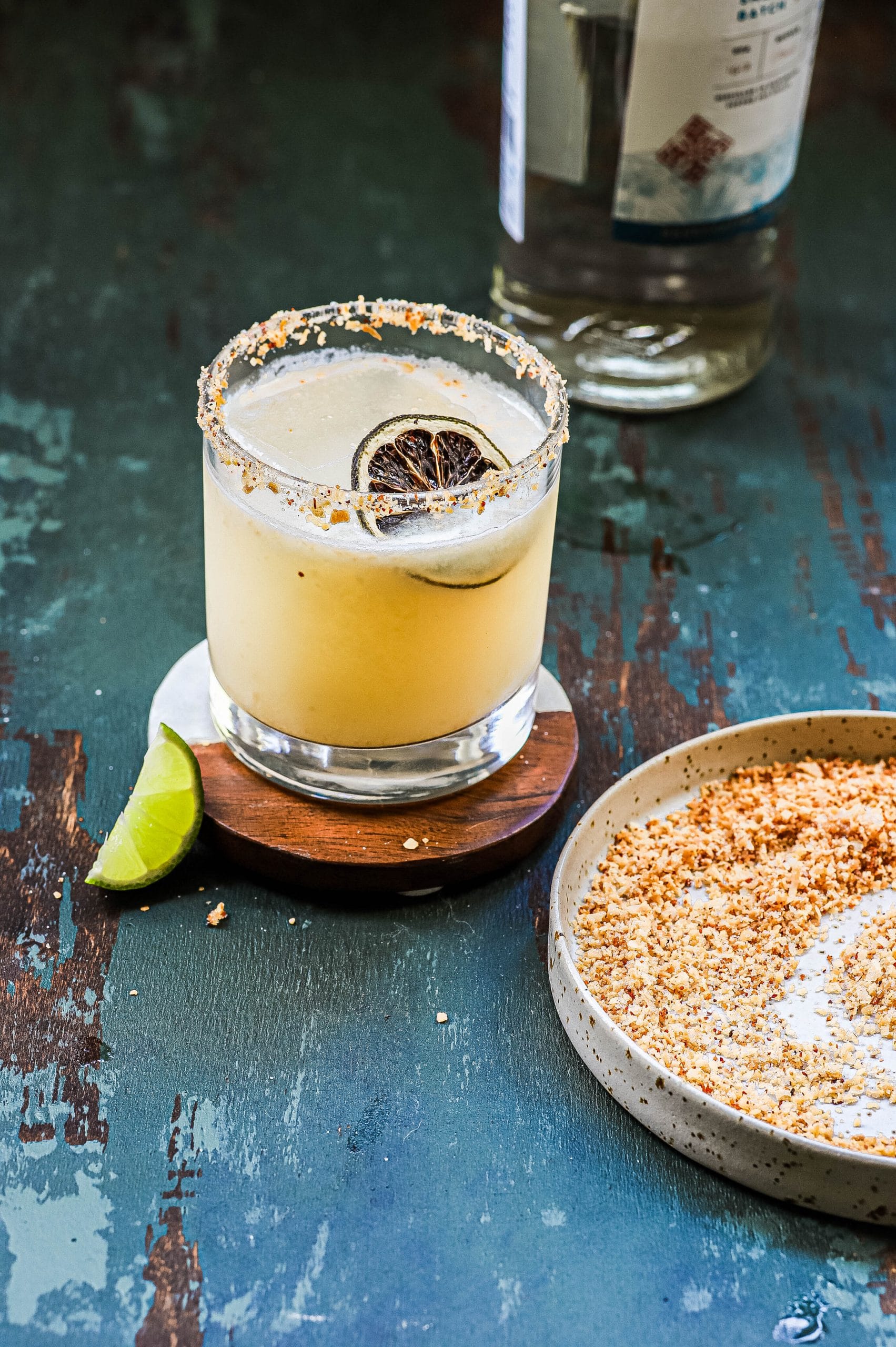 A coconut margarita next to a dish of toasted coconut 