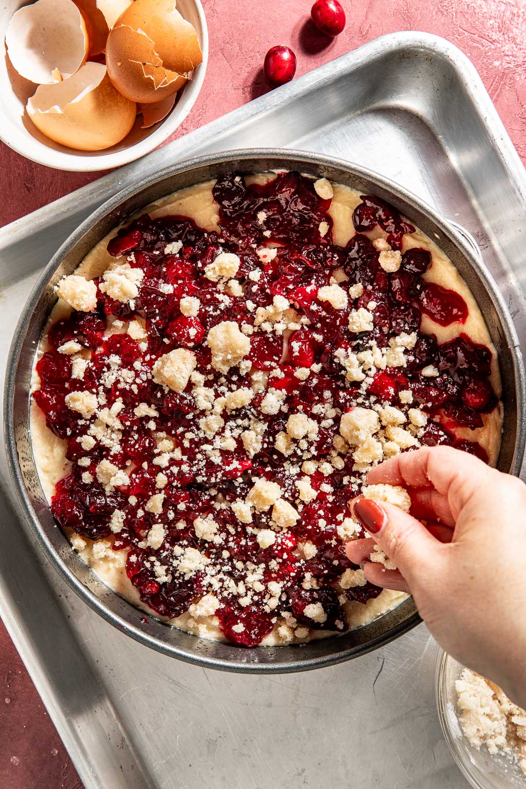 sprinkling streusel on the cranberry ricotta cake before baking