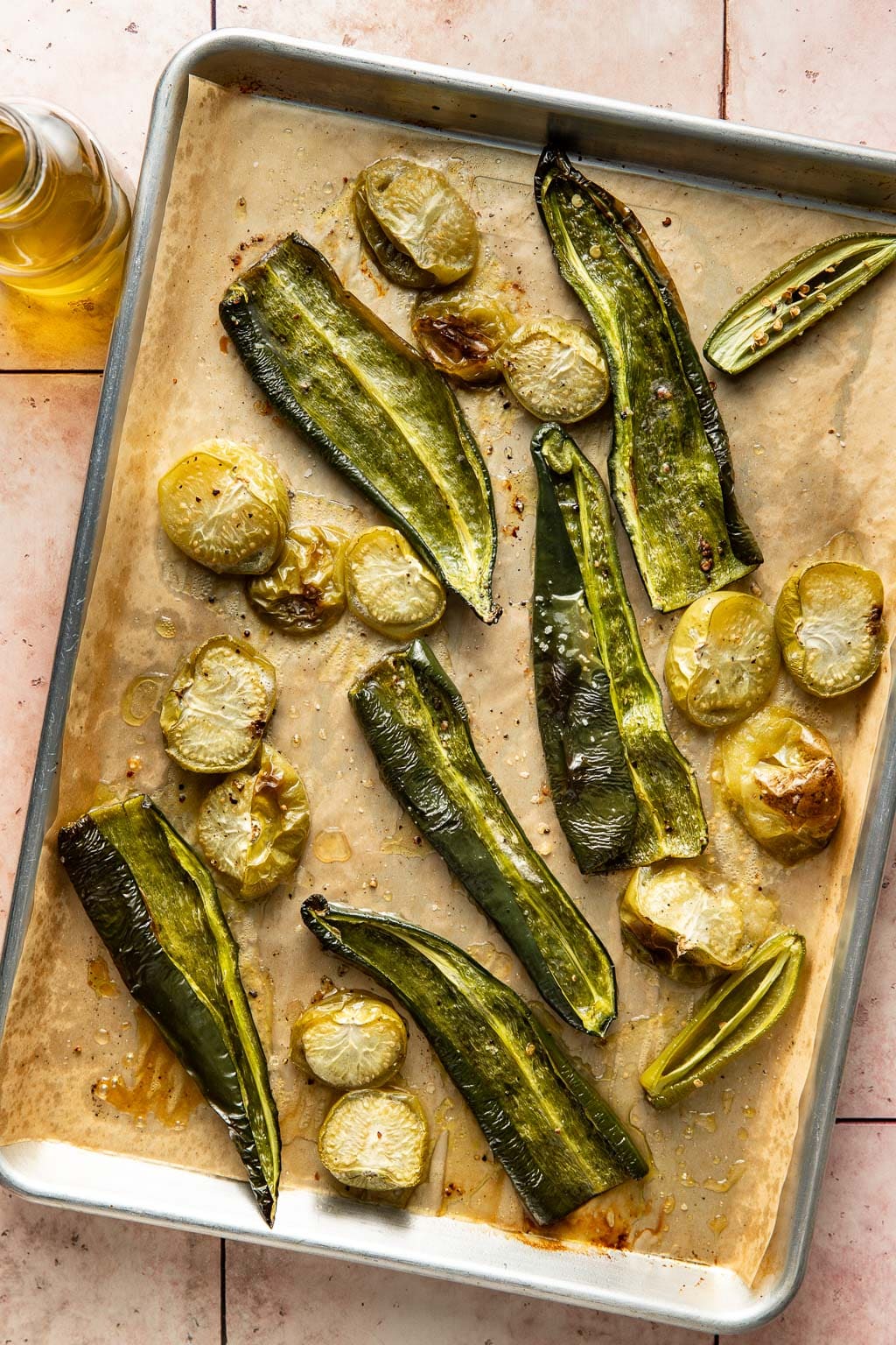 Poblano, tomatillos, and jalapeno on a baking sheet after roasting