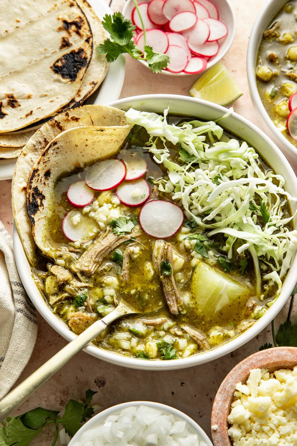 pork pozole verde in bowl with toppings and charred tortillas