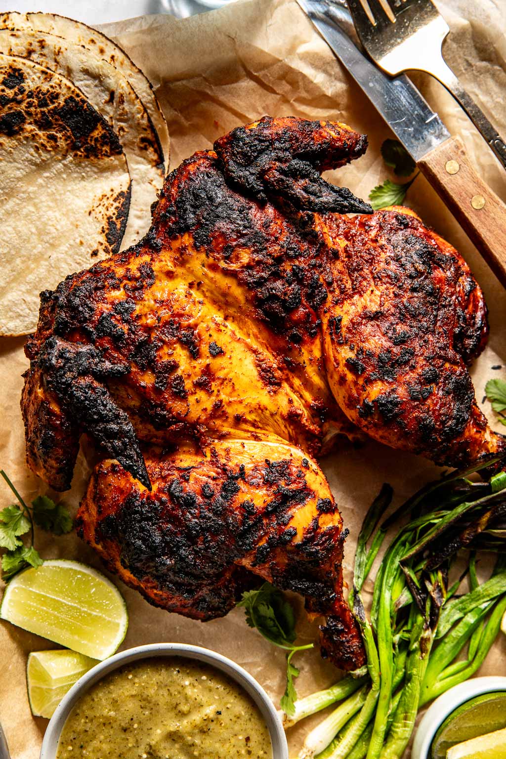 finished pollo asado surrounded by tortillas and salsa