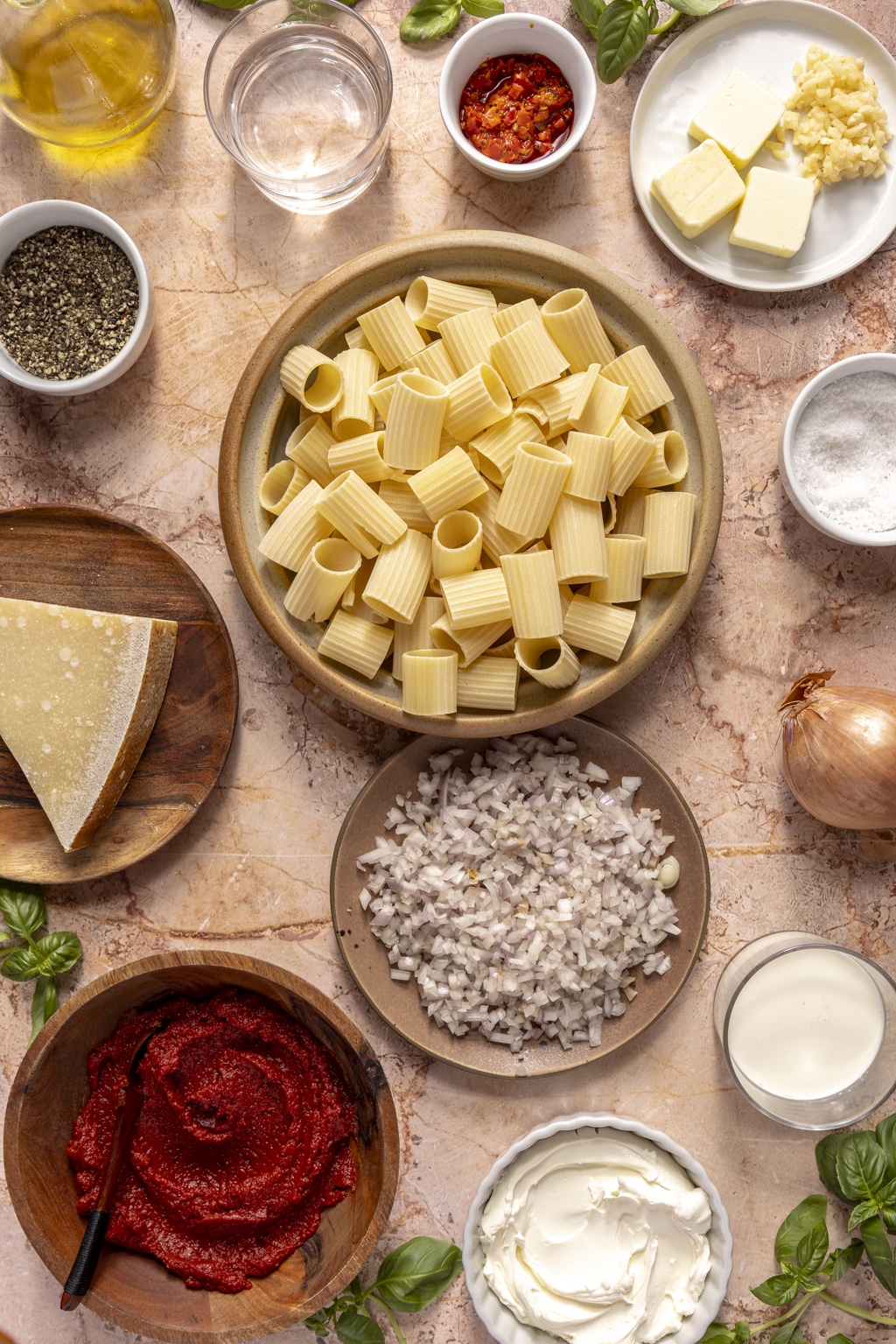 ingredients for pasta alla vodka laid out on a pink background