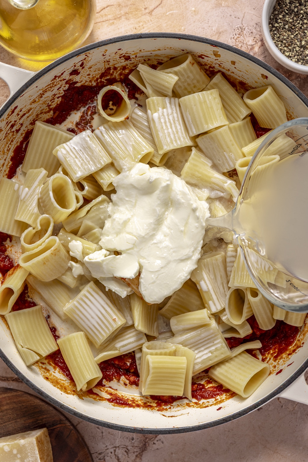 pasta and mascarpone being stirred into the tomato sauce