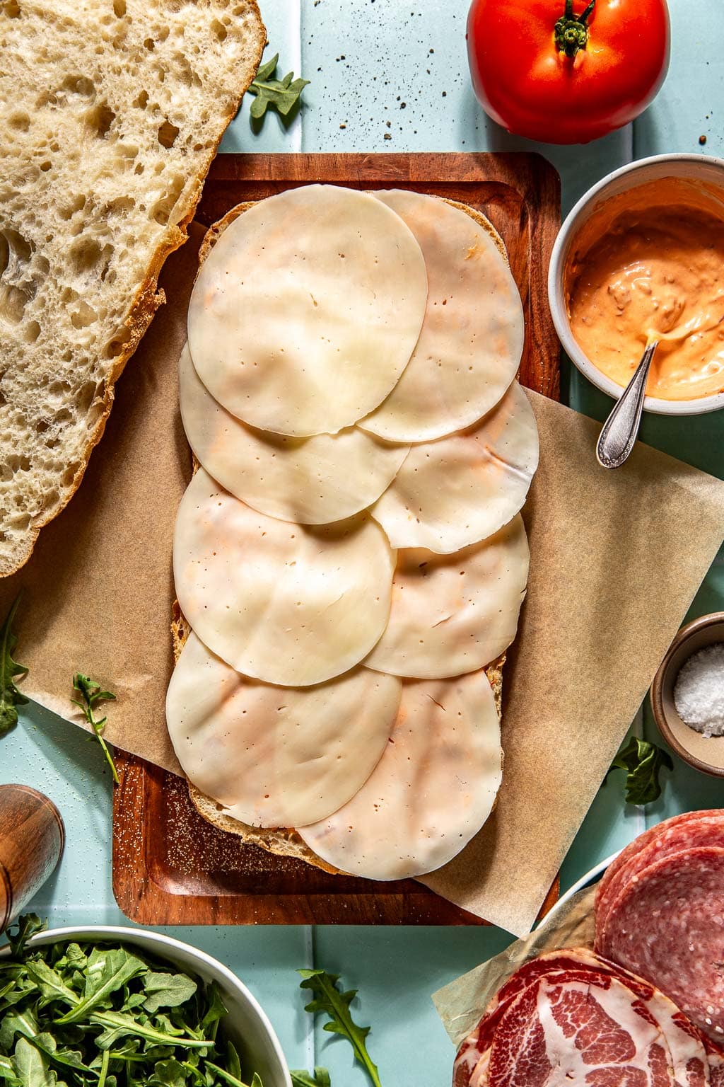 Sliced provolone being added to an Italian picnic sandwich