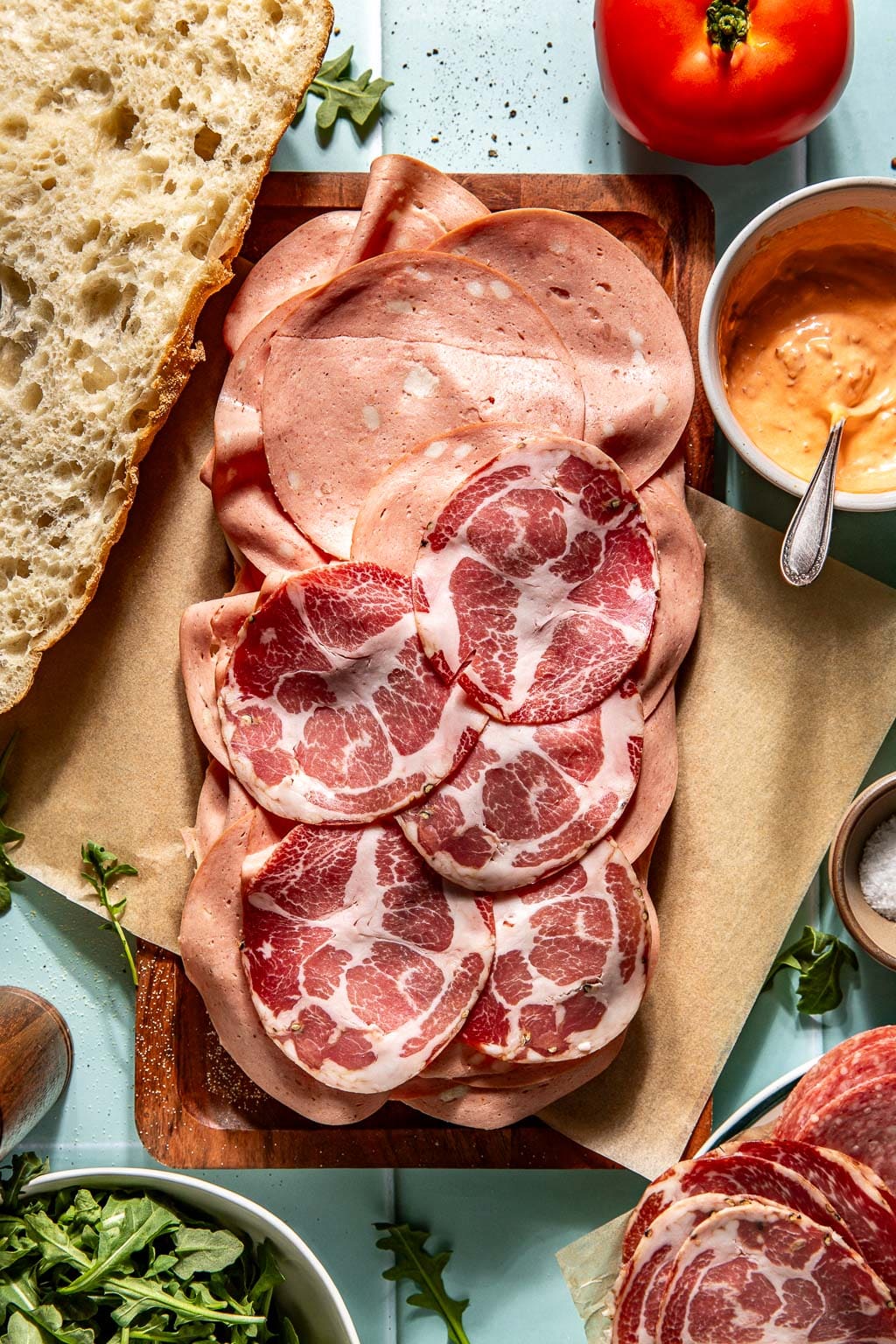 Italian meats being added to an Italian picnic sandwich