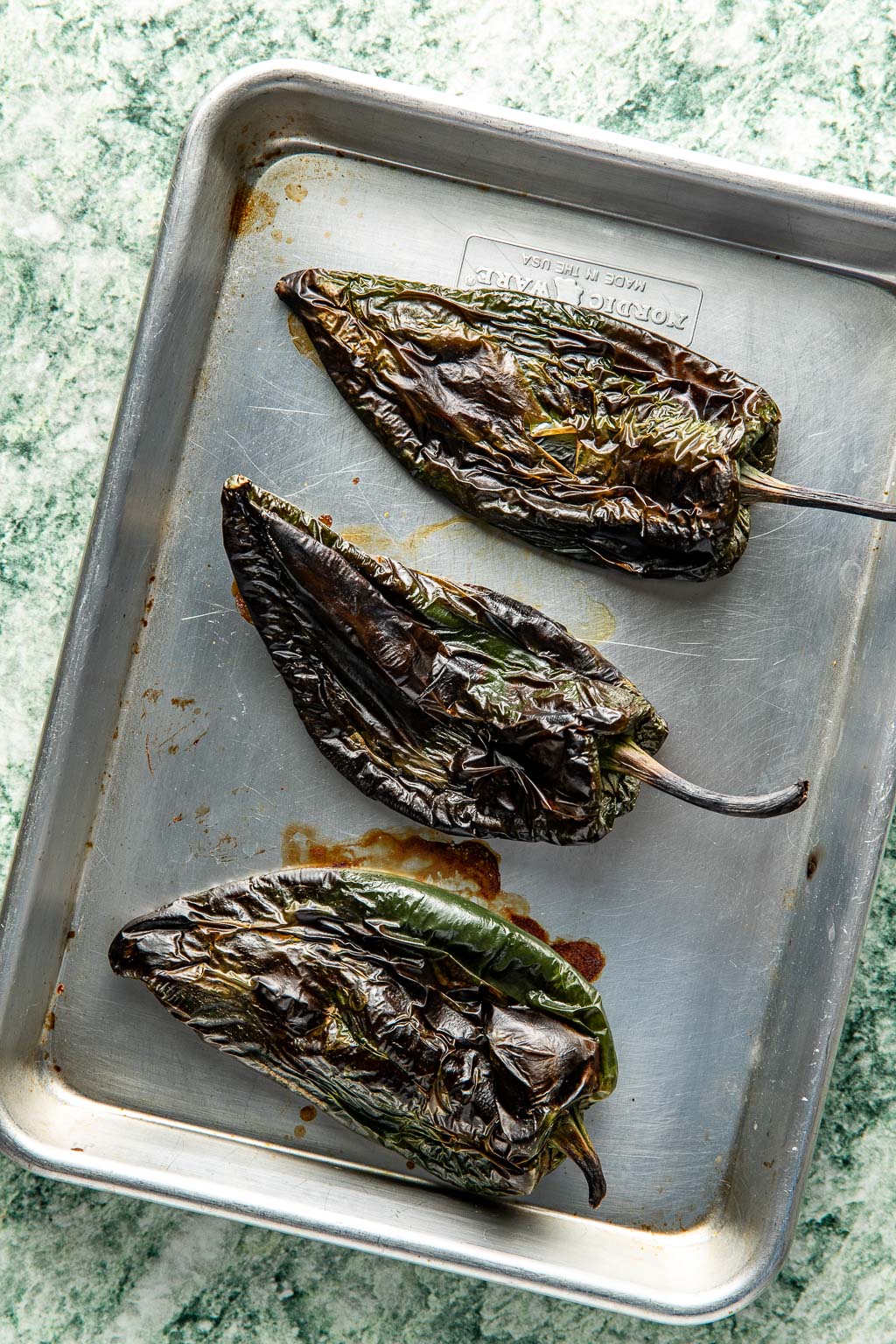 charred poblano peppers on a baking sheet 