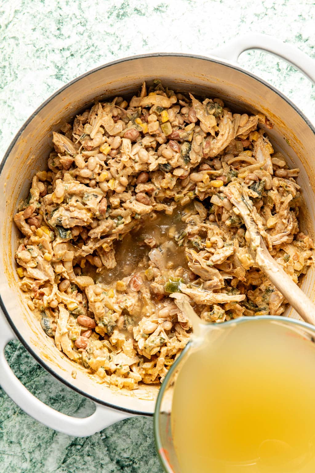 pouring the liquid in the white chicken chili