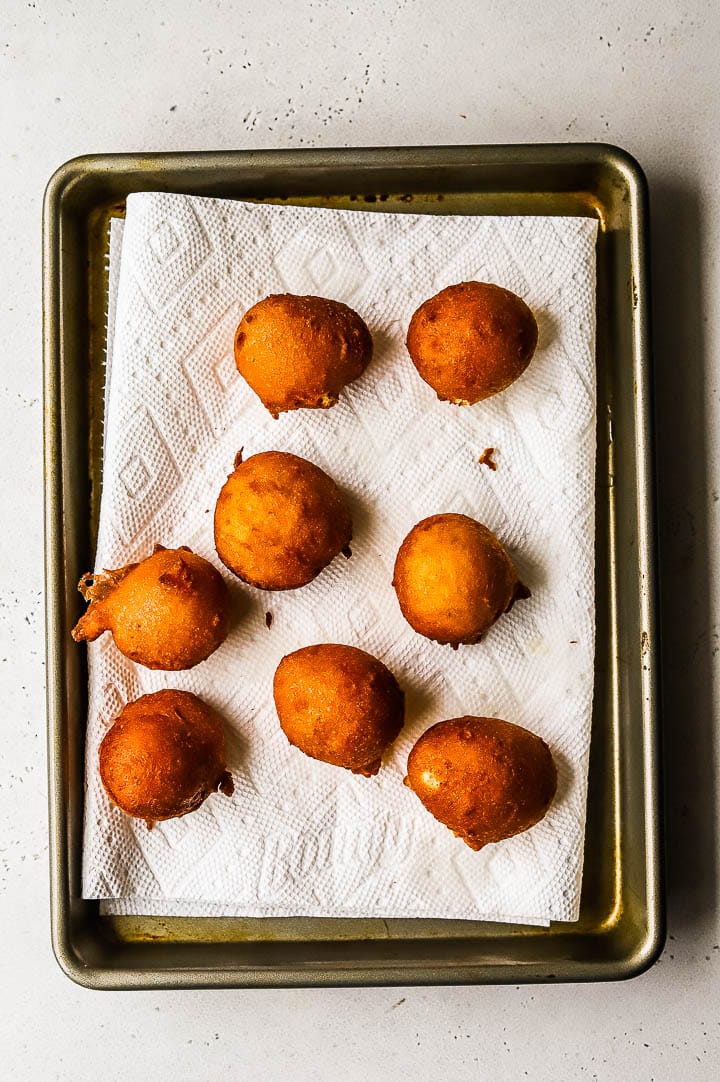 lemon fritters draining on a paper towel lined tray