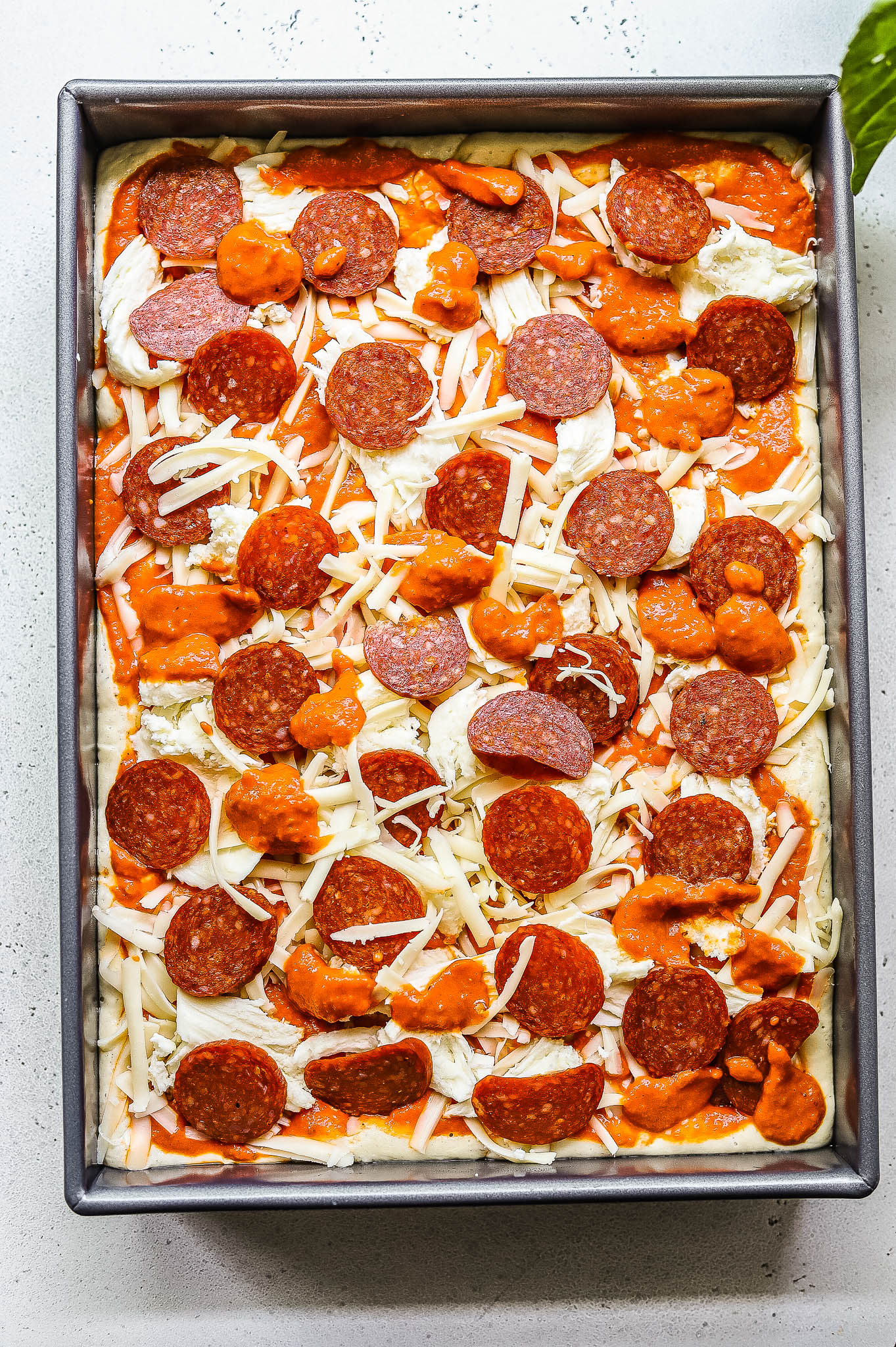 A vodka sauce pizza topped with pepperoni, ready to be baked