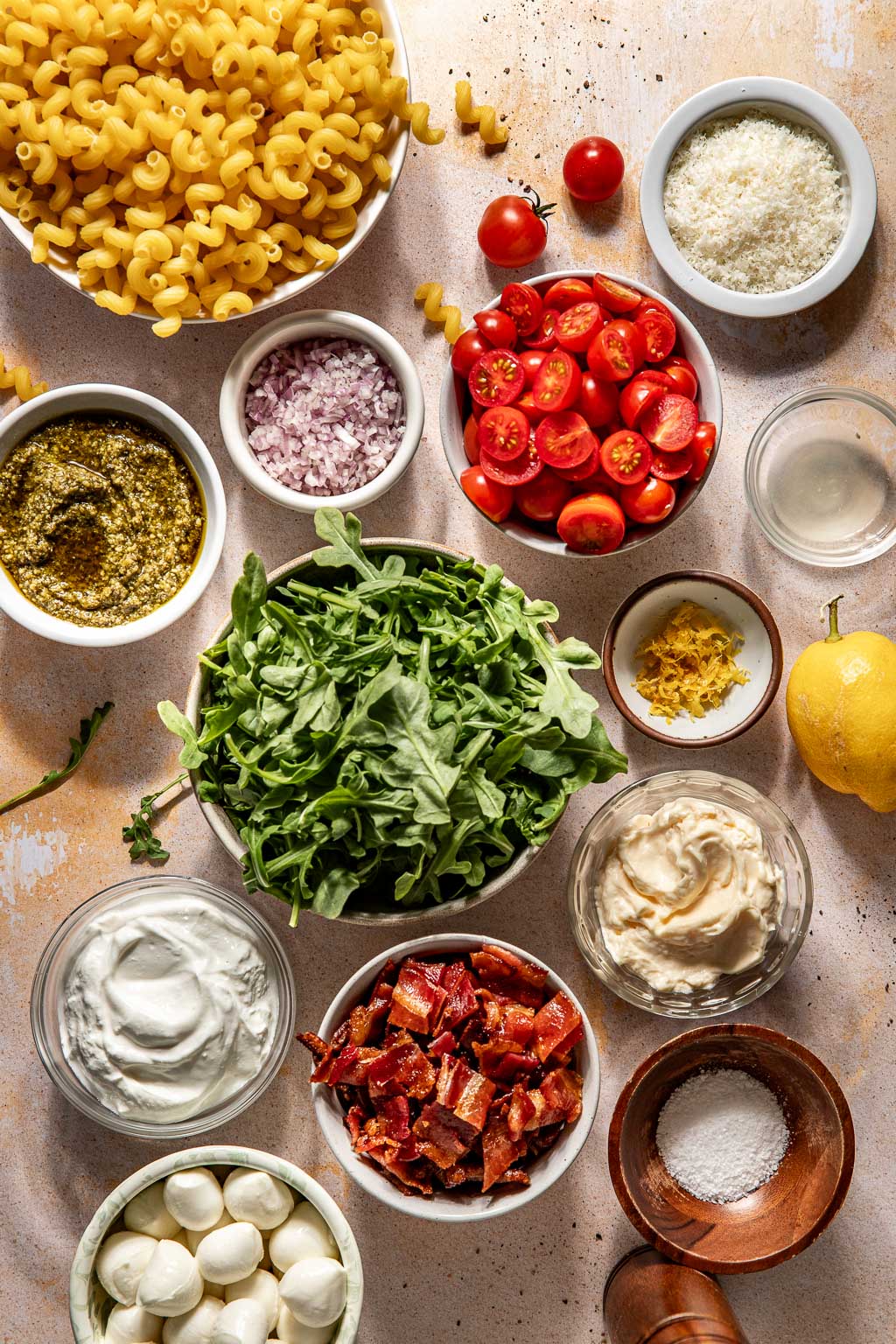 creamy pesto pasta salad ingredient laid out on a tan background