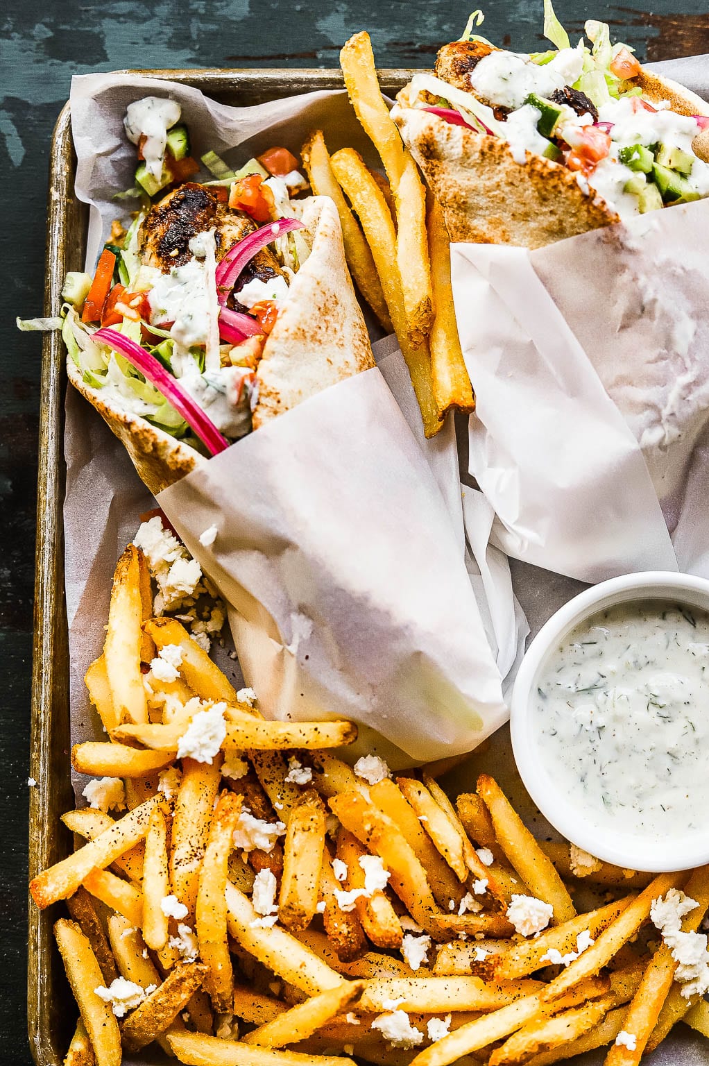 greek chicken pitas on a sheet pan with fries