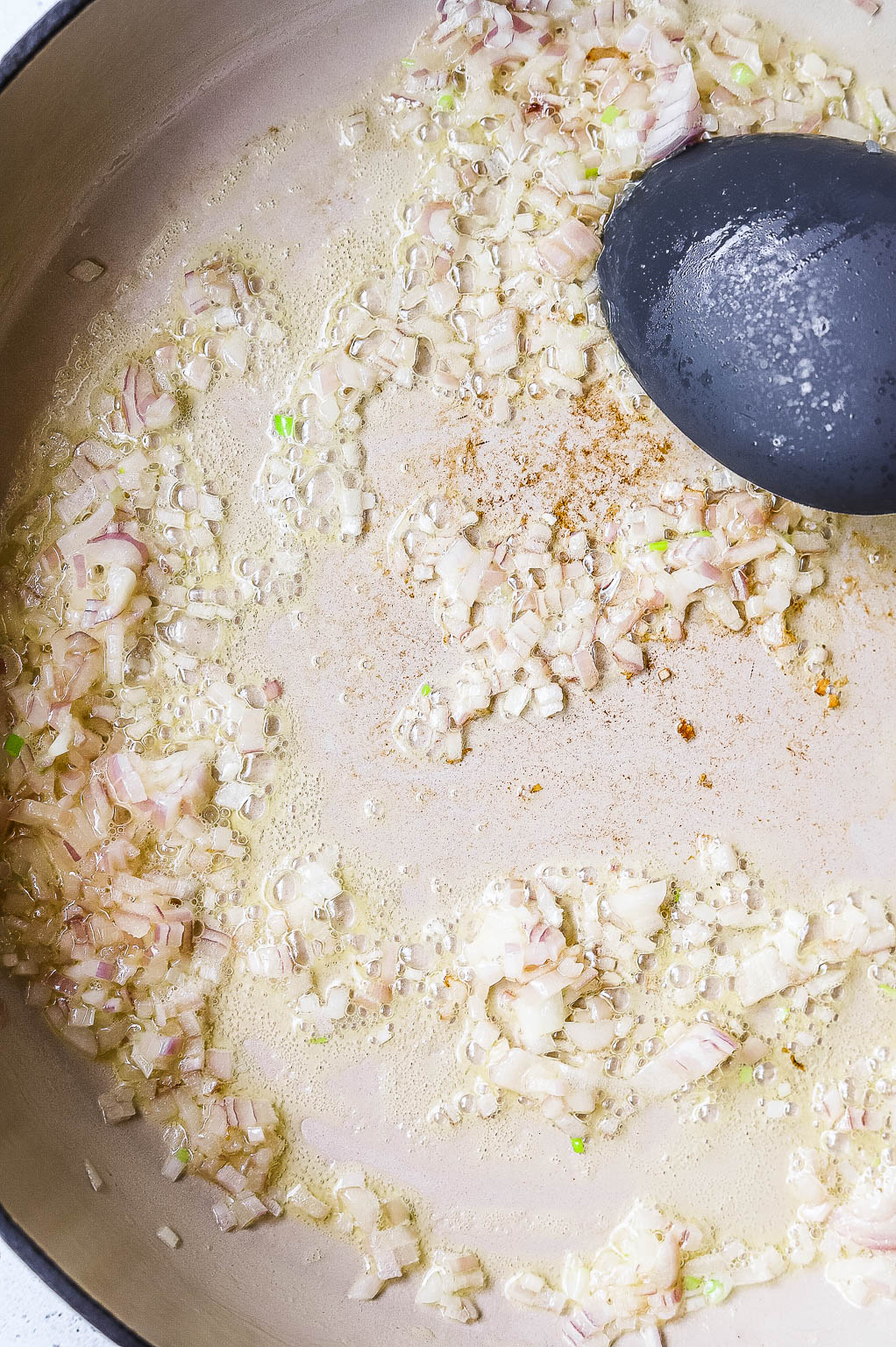 Diced shallot sweating in a skillet 