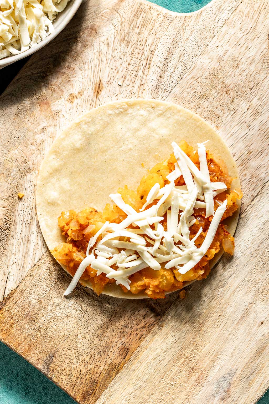 Corn tortillas being filled with potato taco filling. 