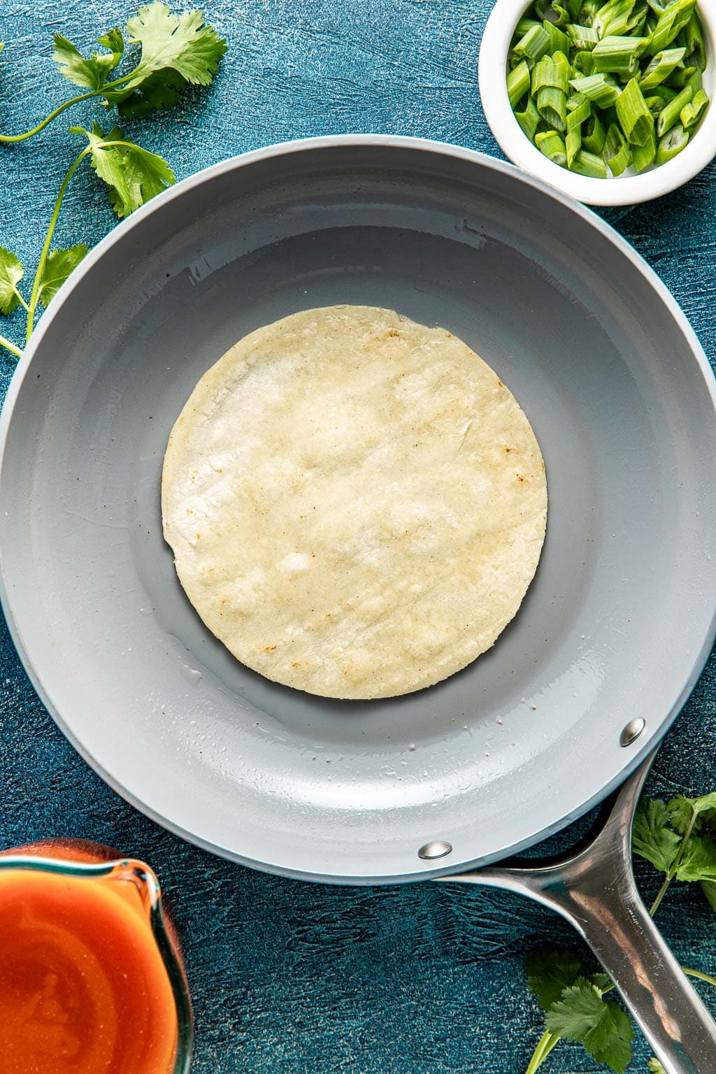 frying a corn tortilla in a skillet