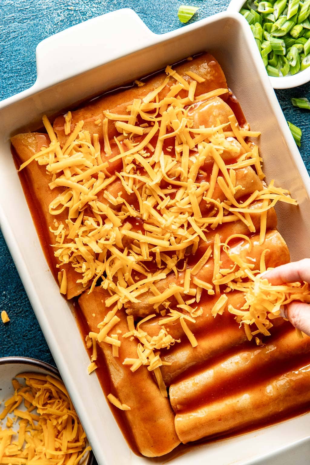 red chicken enchiladas in a baking dish before baking