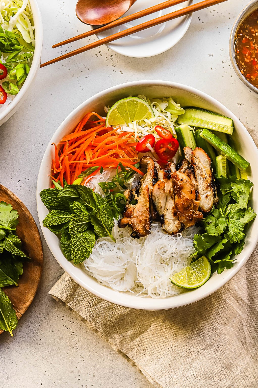 a chicken vermicelli bowl topped with fresh herbs and lime