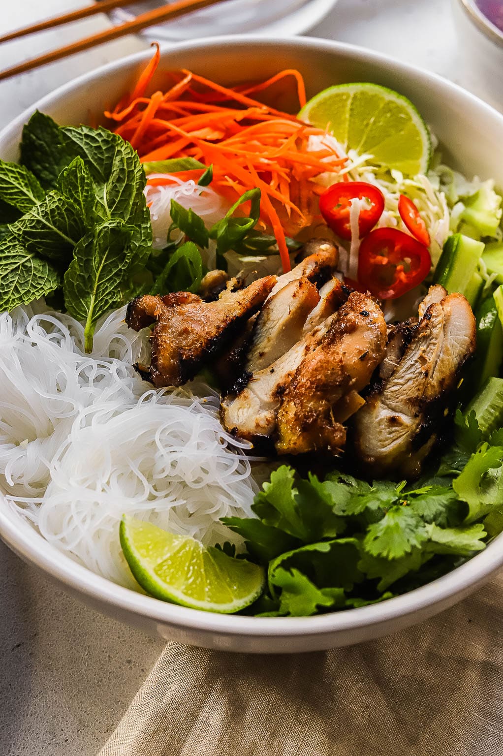 a chicken vermicelli bowl topped with fresh herbs and lime
