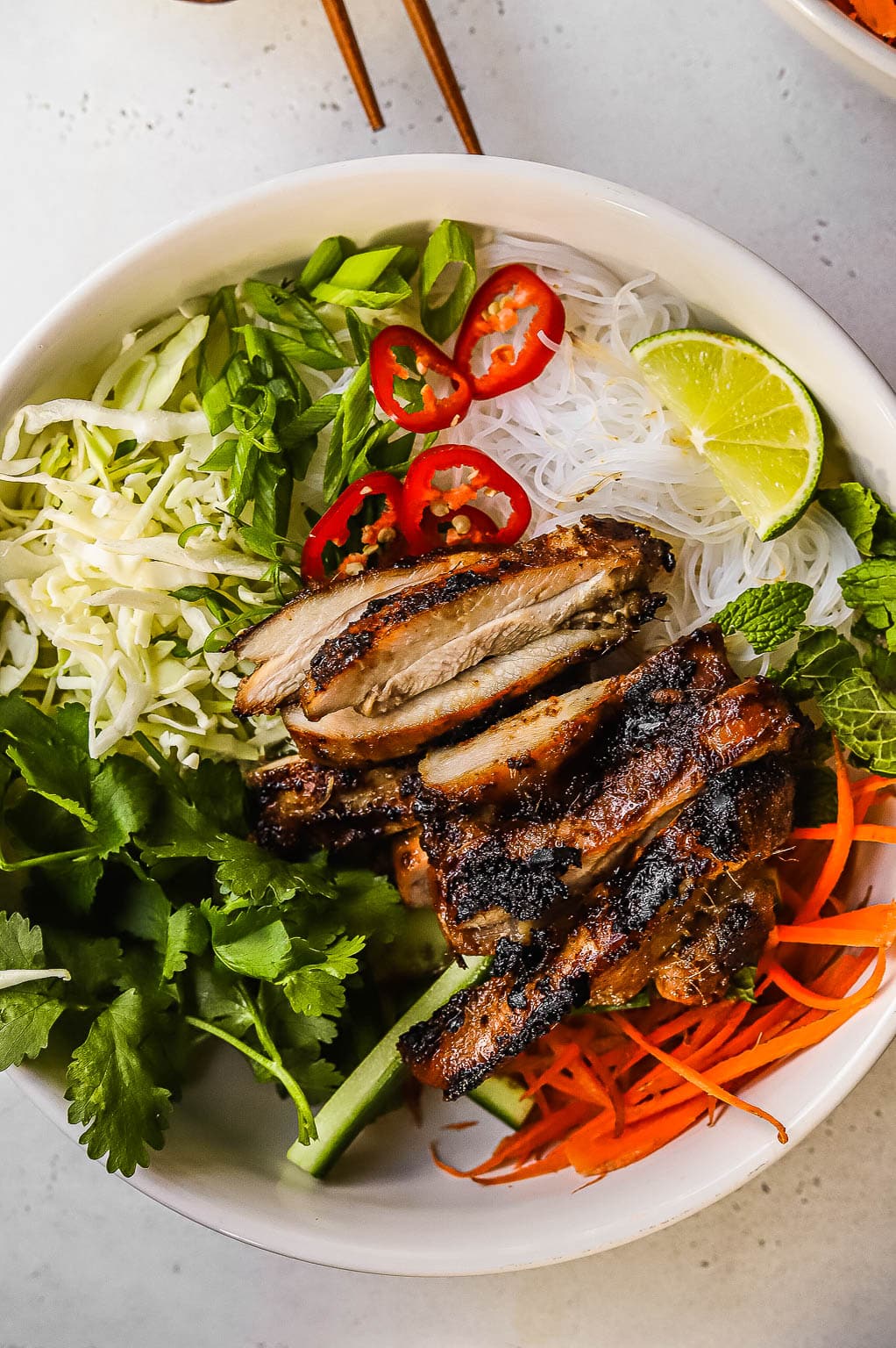 a chicken vermicelli bowl topped with fresh herbs and lime