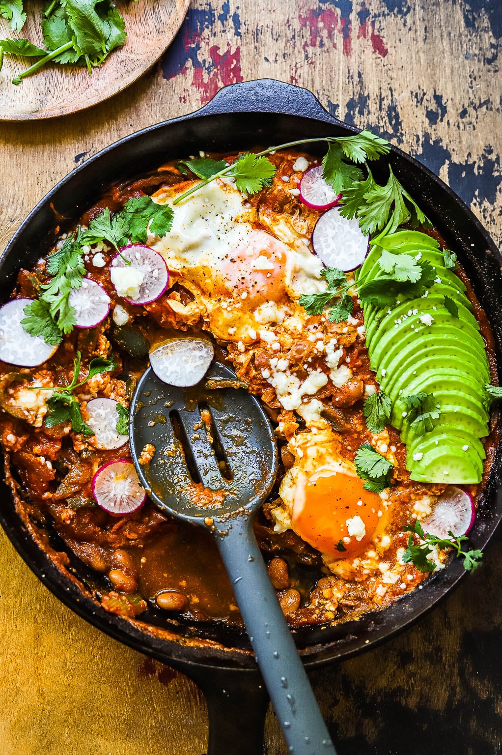 skillet huevos rancheros with avocado and radish on top 