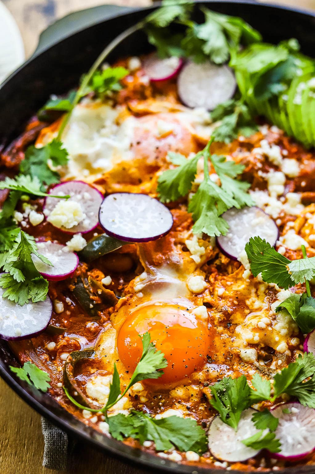 Mexican huevos rancheros skillet topped with avocado and radish 