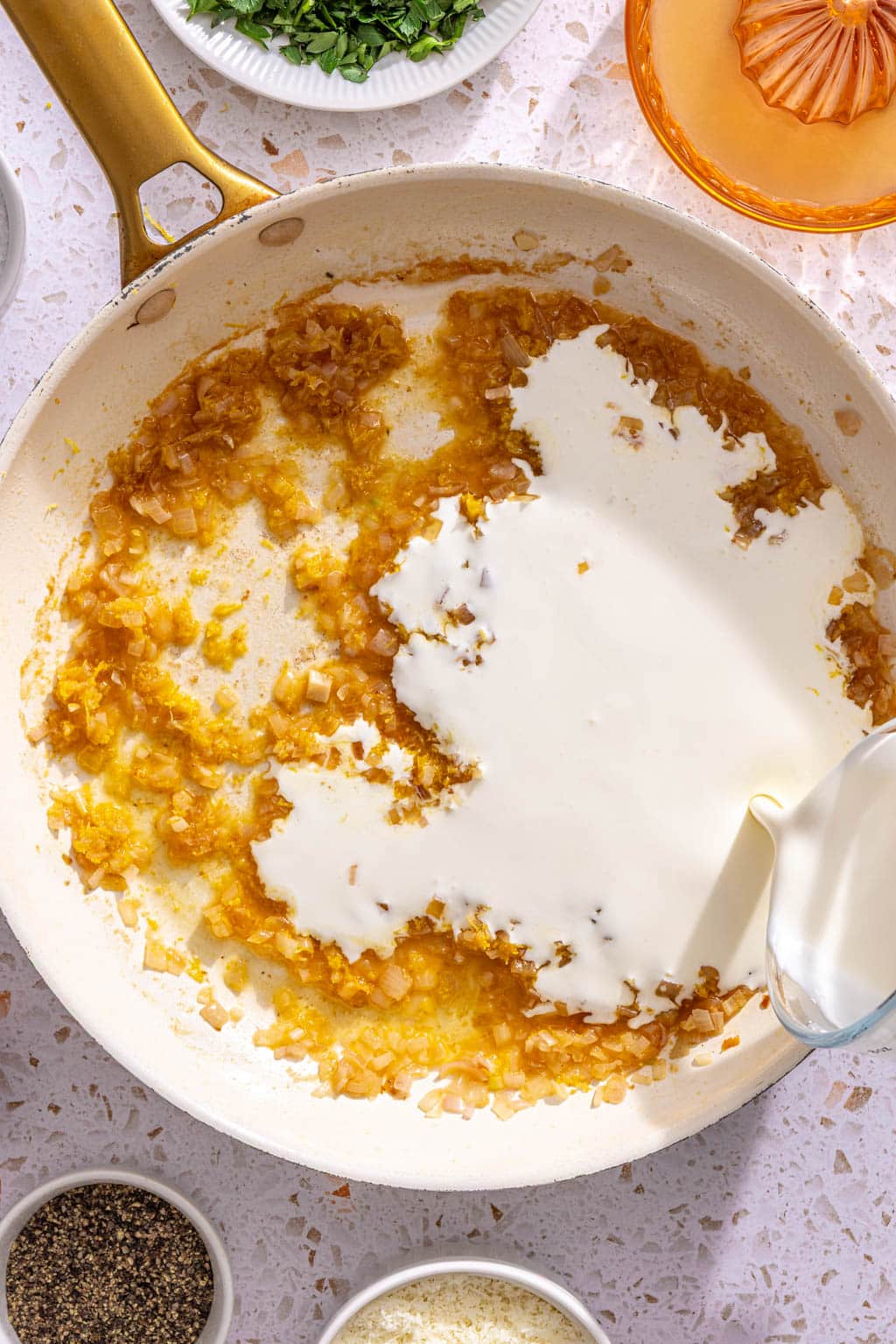 Heavy cream and lemon zest being added to the skillet