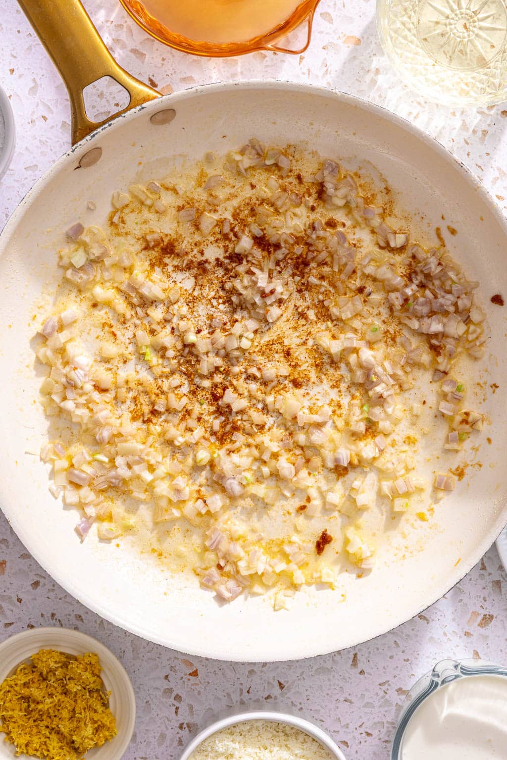 Garlic, red pepper flakes, and shallots being cooked in butter in a skillet