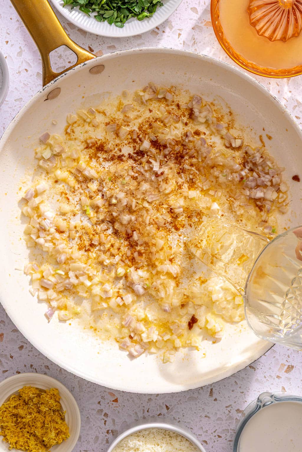 Wine being added to the garlic and shallot in the skillet
