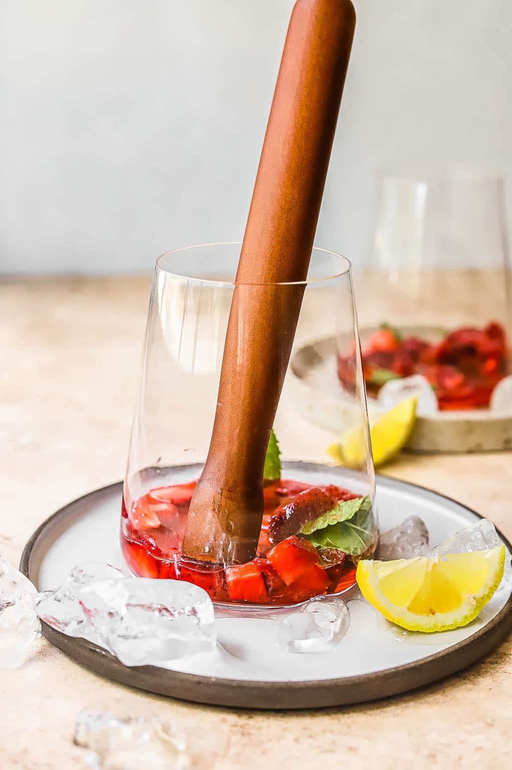 muddling strawberries, syrup, and mint in a glass 