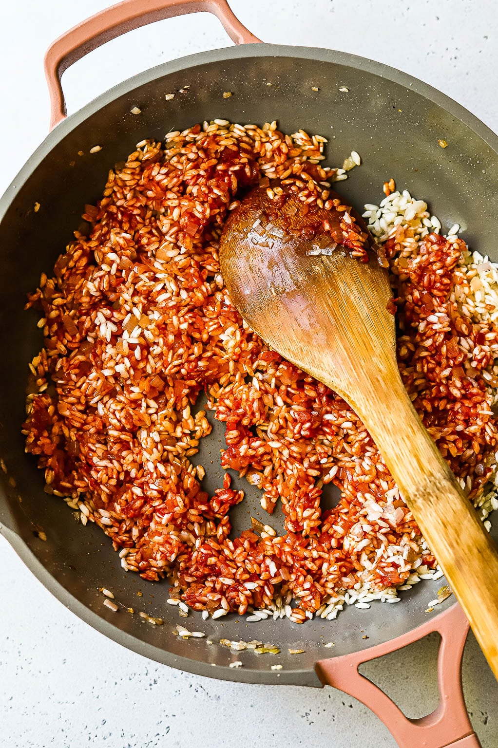 Risotto rice being stirred into tomato paste 