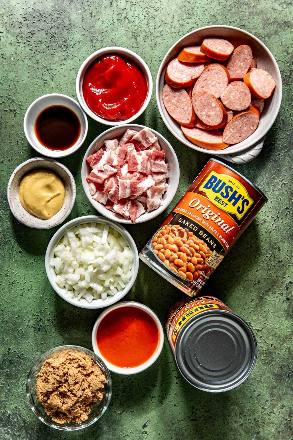 ingredients for dressed up baked beans laid out on a green background