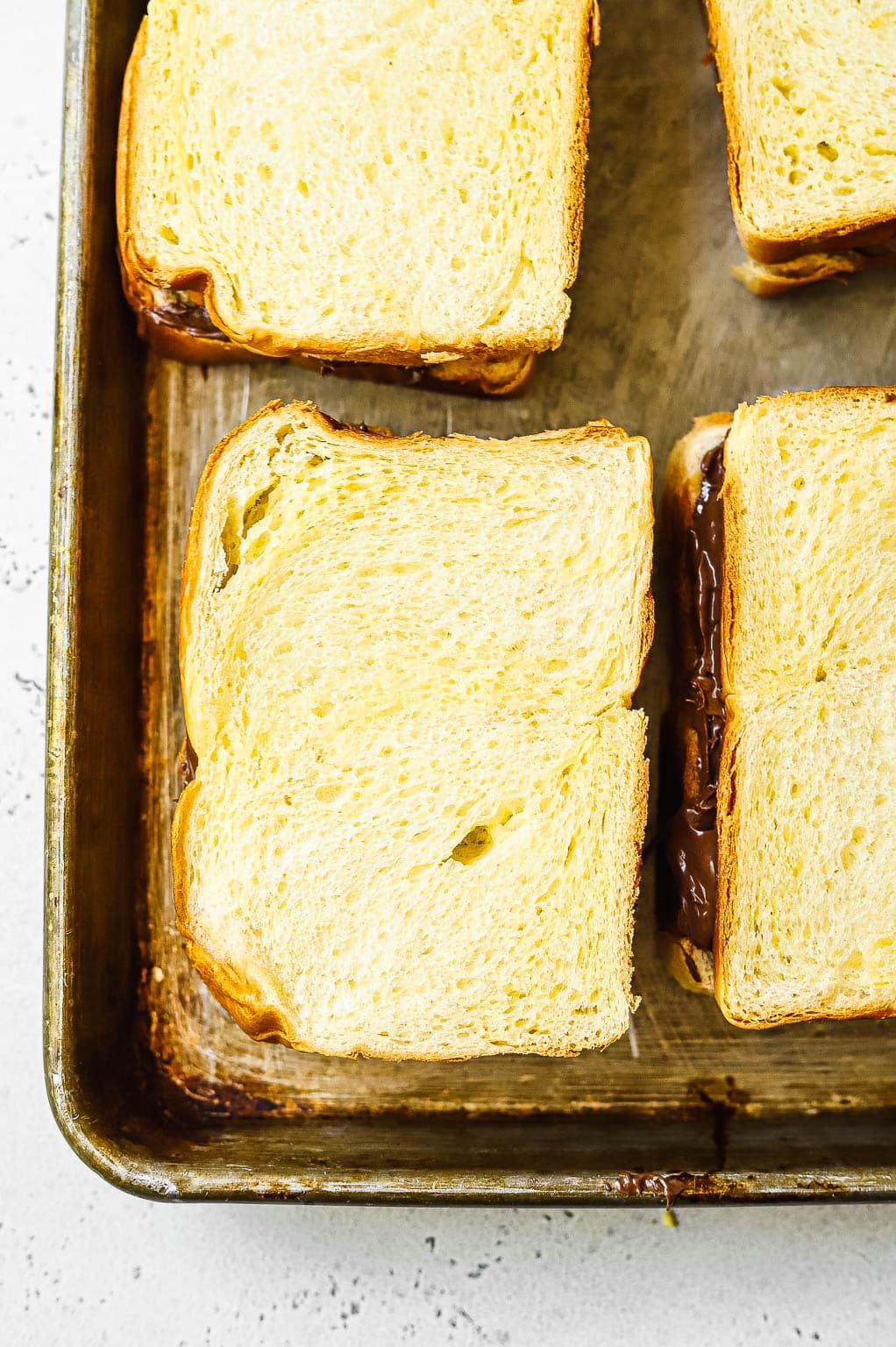 Nutella stuffed brioche bread slices on baking sheet 